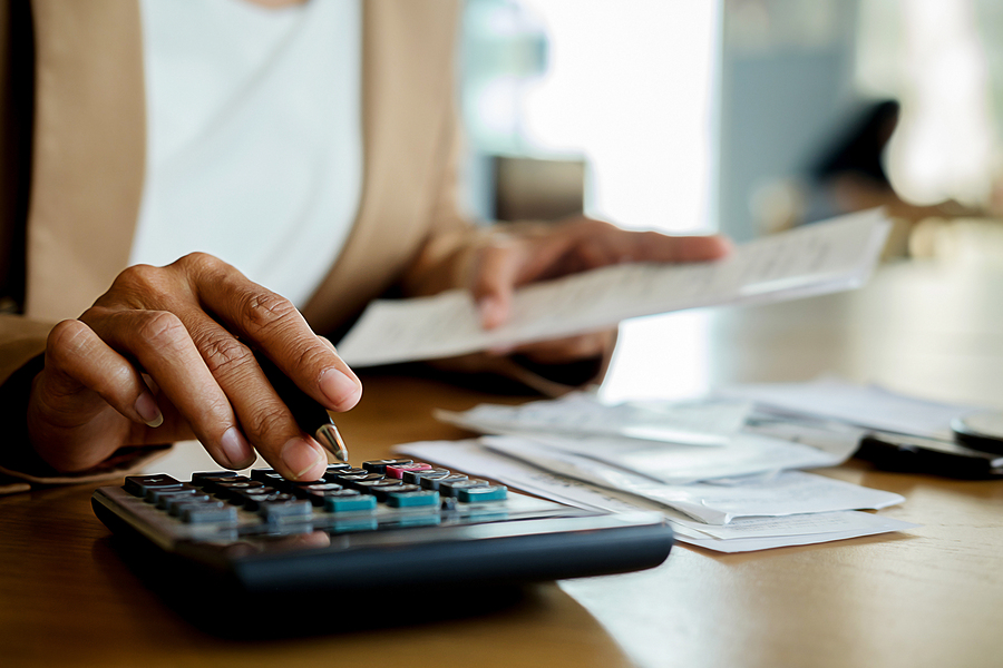 Woman With Bills And Calculator. Woman Using Calculator To Calcu